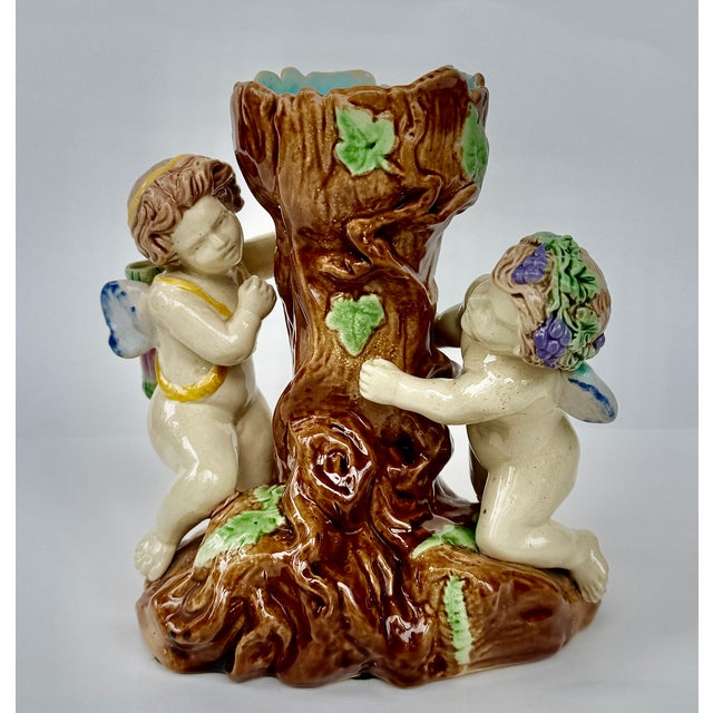 Charming antique majolica spill vase with playful cherubs climbing a tree trunk, finished in rich, colorful glaze. A late...