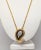 Goldtone paisley shaped pendant with pavé round clear rhinestones in the center with a black resin? border and more pavé...