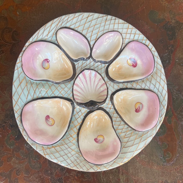 This antique Carl Tielsch porcelain oyster plate features distinctive pink luster wells and a central shell motif, dating...