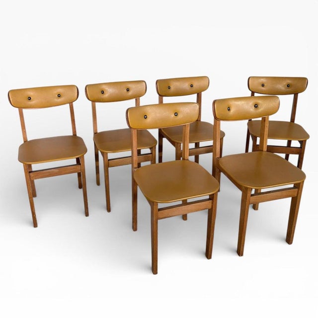 A charming set of six mid-century dining chairs featuring classic butterfly back silhouettes with mustard-yellow vinyl...