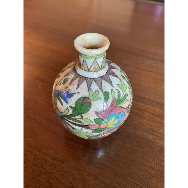 A Persian ceramic vase from the Qajar dynasty. Brightly painted with flora and geometric patterns on a cream colored...