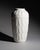 A tall monochrome floor vase with rhythmic relief decoration resembling stylised leaves or feathers. The glossy white...