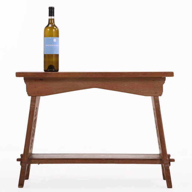 Executed in solid oak, the table features a thick rectangular top raised on boldly shaped trestle-form supports joined by...