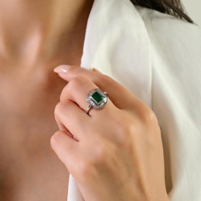 This elegant halo ring features 1 emerald-cut natural green emerald totaling 1.06 carats, set in 14k white gold. The...