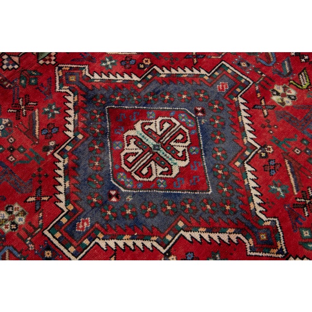 Beautiful vintage Persian Shiraz hand-knotted wool rug with a red color field. This piece has a beige frame and multicolor...
