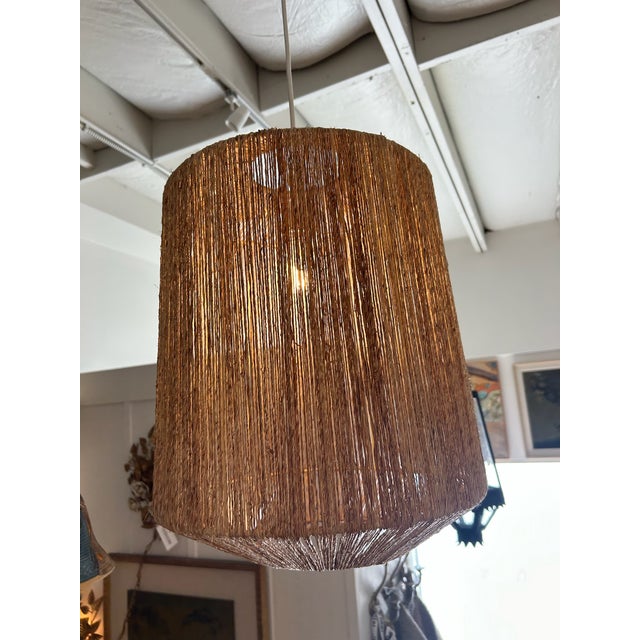 Textural woven pendant light featuring a warm, organic silhouette with softly tapered drum form. The natural fiber...