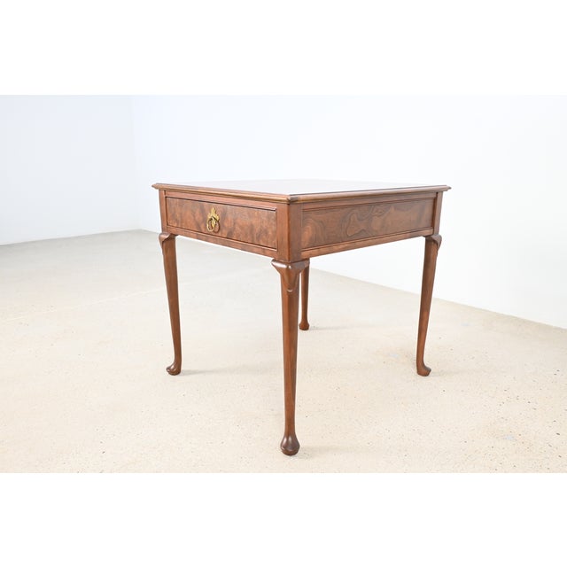 This elegant Baker Furniture Queen Anne end table is beautifully crafted in rich walnut with a striking burl wood drawer...