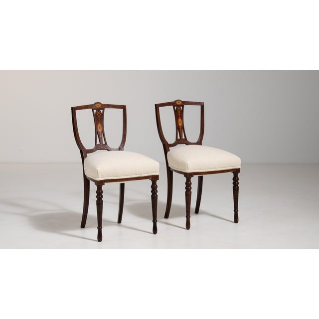 Executed in the refined tradition of the Empire style, this distinguished pair of English accent chairs from the 19th...