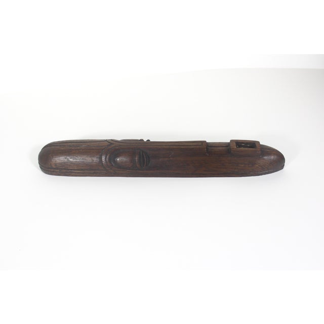 This hand carved face mask is long and narrow. The smooth dark wood has nice graining. There is a notch at the top on the...