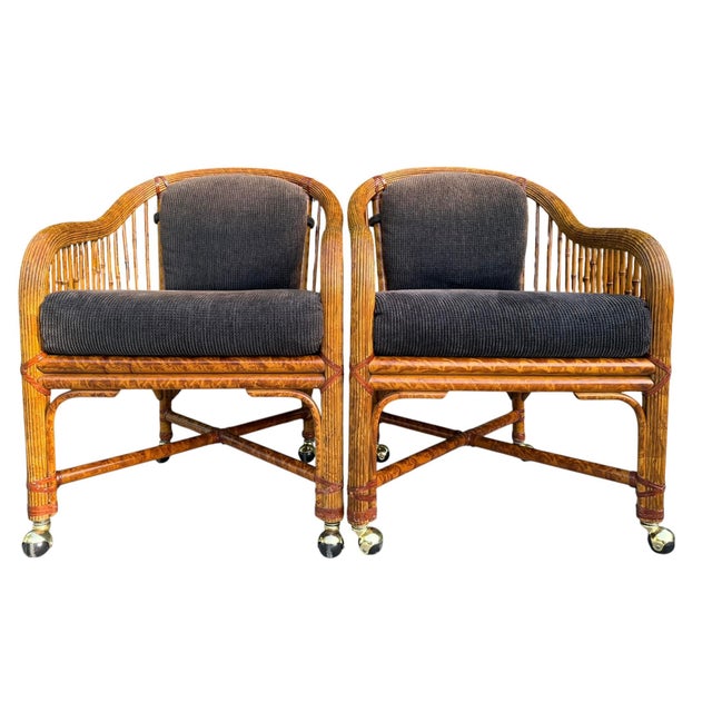 A handsome pair of vintage rattan lounge chairs featuring a classic burnt bamboo finish, faux bamboo styling, woven cane...