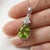 This vibrant pendant features a refreshing Peridot, a gemstone celebrated for its lively lime-green hue and natural...