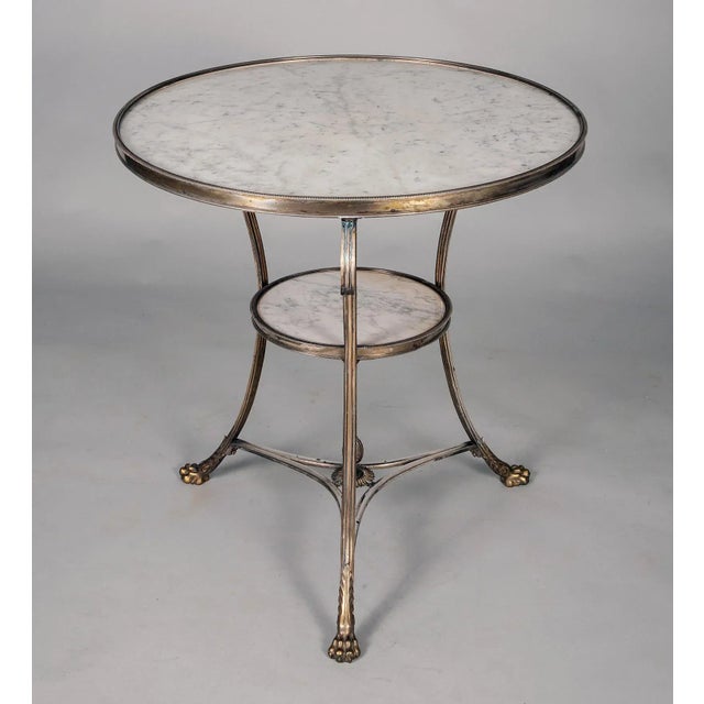 Louis XVI style circular silvered bronze gueridon with black and white marble inset inside a reeded frame. The table is...