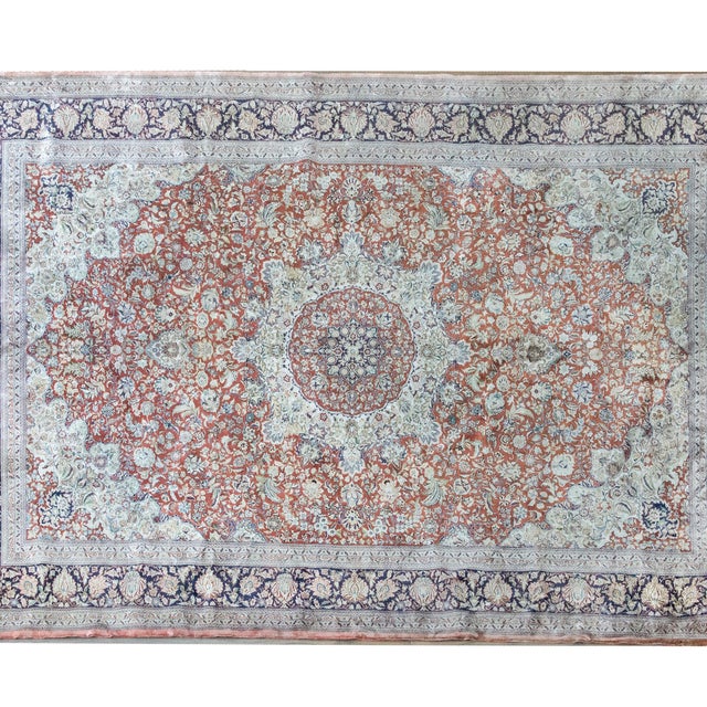 A wonderful late 20th century Persian hand-knotted silk rug featuring a central medallion woven with myriad flowers, and...