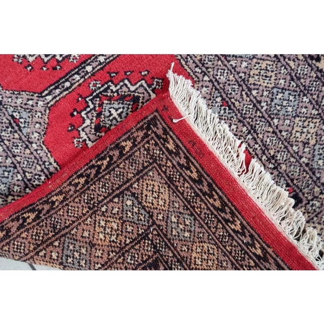 An exceptional Mid-Century Vintage Uzbek Bukhara Style Wool Runner Rug hand-knotted in Uzbekistan. Bukhara-style rugs are...
