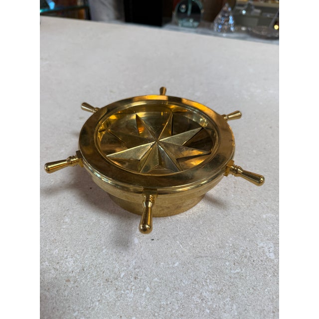 Distinctive vintage brass ashtray designed in the form of a nautical ship’s wheel, featuring a sculptural starburst...