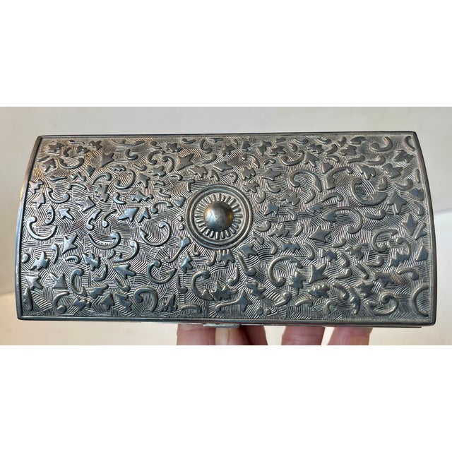 Decorative rectangular jewelry chest in an unknown white metal. It features a curved hinged lid and royal blue textile...