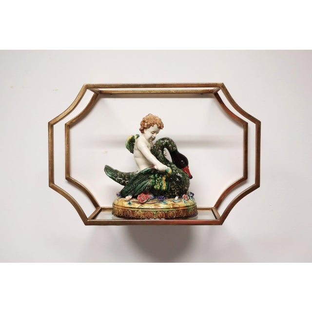 Set of three graduated gold-tone metal and clear glass floating wall shelves featuring curved open-frame silhouettes and...
