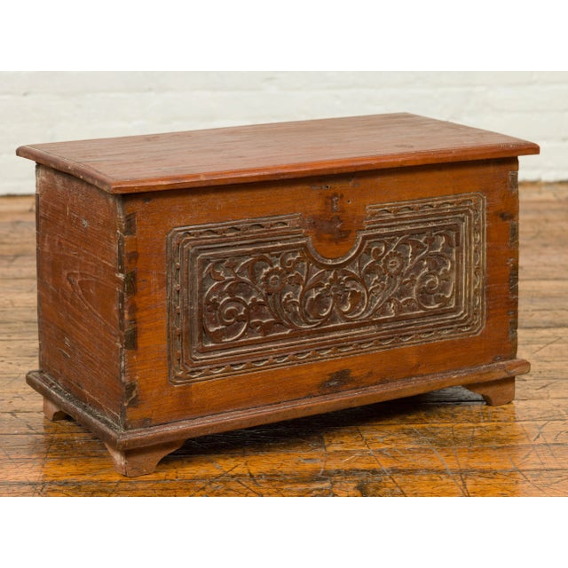 An Indonesian vintage wooden blanket chest from the mid-20th century, with floral carved front, dovetailed construction...