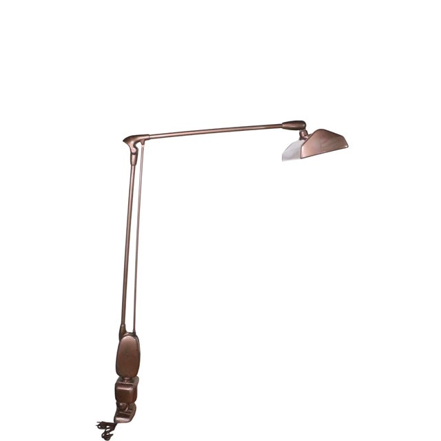 Adjustable desk mount task lamp by Dazor, with two arms, and hood shade. The lamp clamps to a horizontal surface, and will...