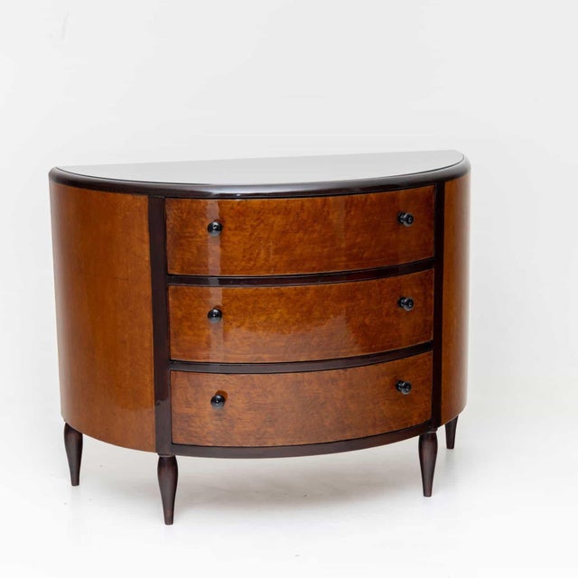 Art Deco chest of drawers in demi-lune shape with three drawers and inlaid glass top. The chest of drawers stands on...
