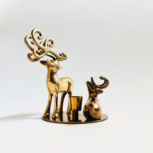 A lovely vintage brass deer candle holder. Features 2 deer mounted to a circular plate with the candle holder in the...