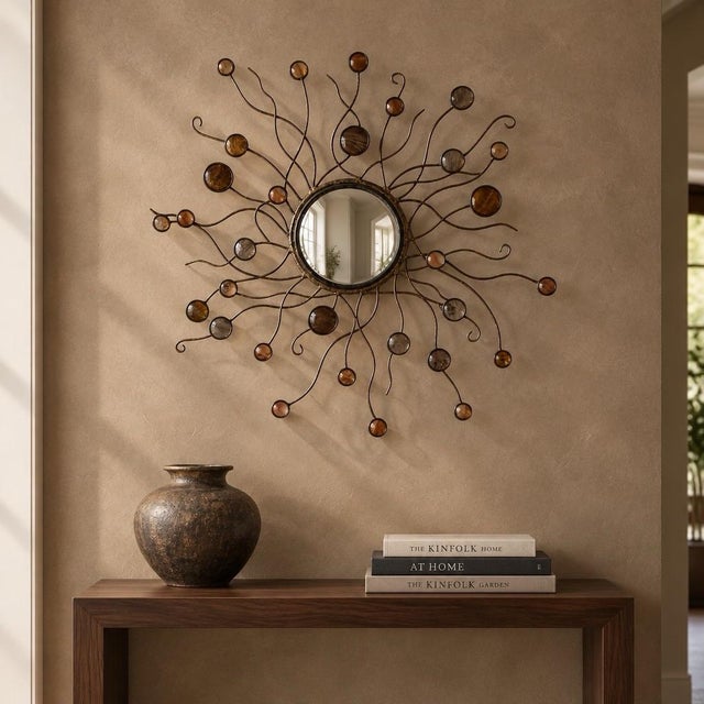 An artisan-made convex center mirror is surrounded by curling metal arms and small round accents inset with Capiz shells....