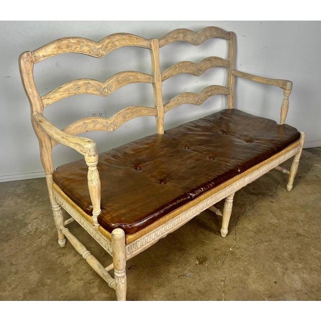 French Provincial style ladder back settee w/ leather cushion & rush seat. The bench stand on six straight legs connected...