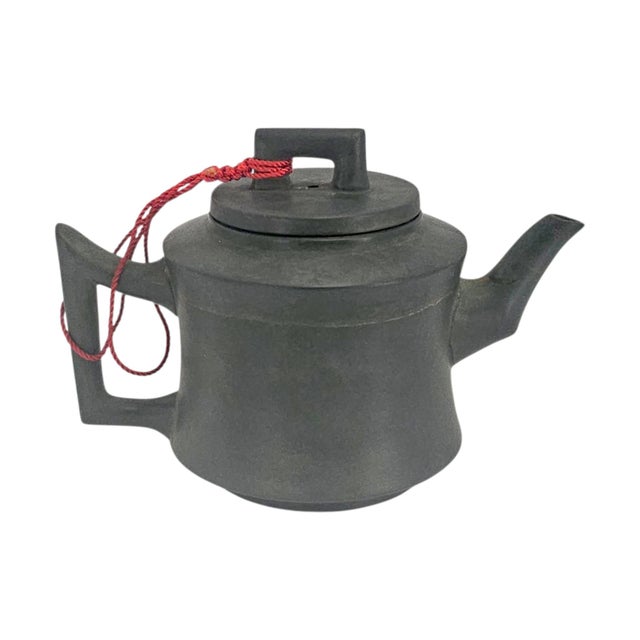 A late twentieth-century Chinese teapot formed in dark unglazed stoneware with a compact cylindrical profile and...
