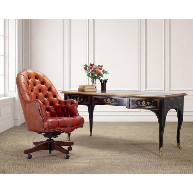 A handsome English Georgian style executive swivel desk chair, upholstered in a rich tufted leather. The chair features a...