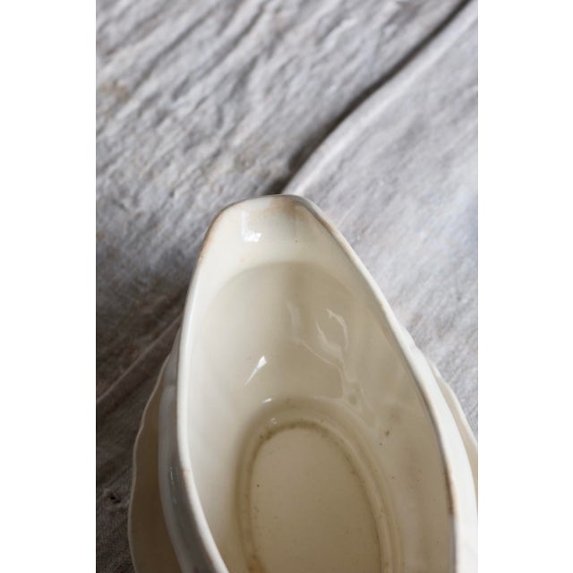 Antique ivory earthenware gravy boat with soft, elegant lines, accompanied by its matching tray. A simple and timeless...