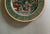 A vintage green & gold Egyptian Revival gold trimmed plate featuring a colorful hunting scene with a hieroglyphic border.