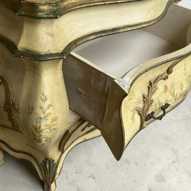 This is a mid-century Italian Venetian hand painted bombe commode with a faux marble top. The chest has a floral motif...
