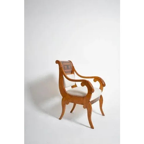 Pair of armchairs in natural wood and veneer with slightly rounded backs decorated with marquetry of facing griffins...