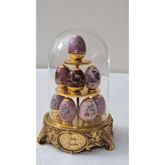 A charming late 20th-century House of Fabergé Ruby Garden miniature egg display, featuring eight richly decorated eggs...