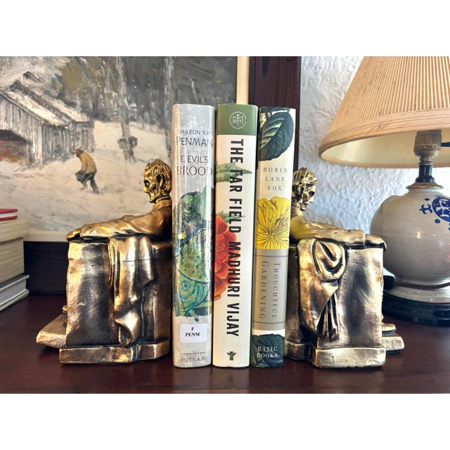 Featuring the 16th President of the United States, this substantial bookend pair depicts Lincoln sitting in a large...