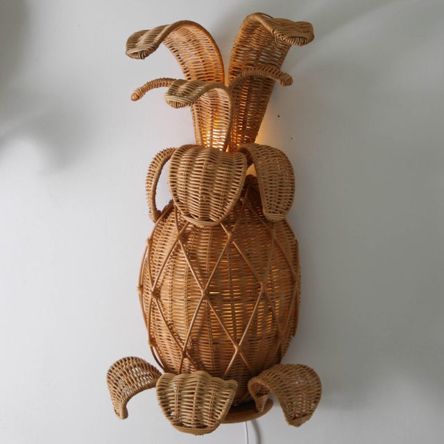 Stunning pair of pineapple-shaped wall sconces in woven wicker. Featuring removable leaves, a hidden light between the...