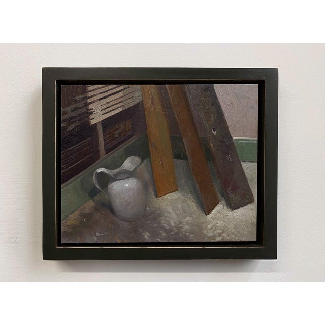 This oil on panel work depicts a simple white pitcher positioned beside weathered wooden planks, set against a softly lit...
