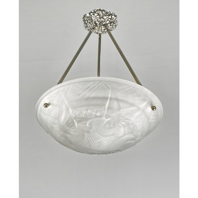 A French art deco pendant light made circa 1930 in nickel plated bronze or solid brass holding a bowl in clear frosted...