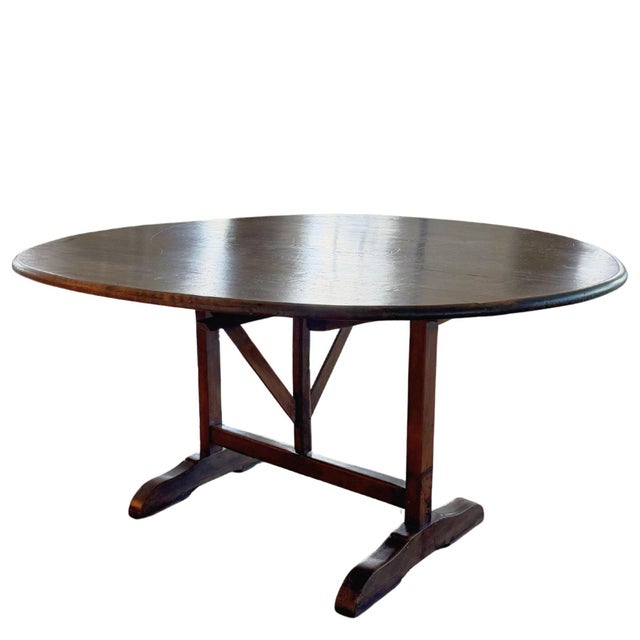 Early 19th century French walnut vigneron wine tasting table with oval tilt-top and traditional trestle base with...