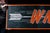 Painted tin advertising sign for WNX (West Nebraska Express), featuring bold block lettering in orange set against a deep...