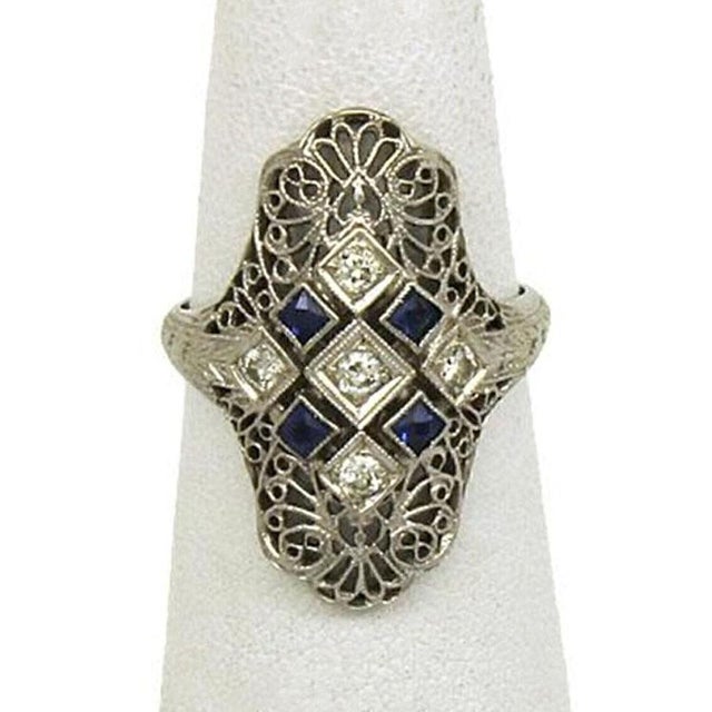 This Art Deco diamond and sapphire ring is a stunning piece of fine jewelry, crafted in 18k white gold with intricate...