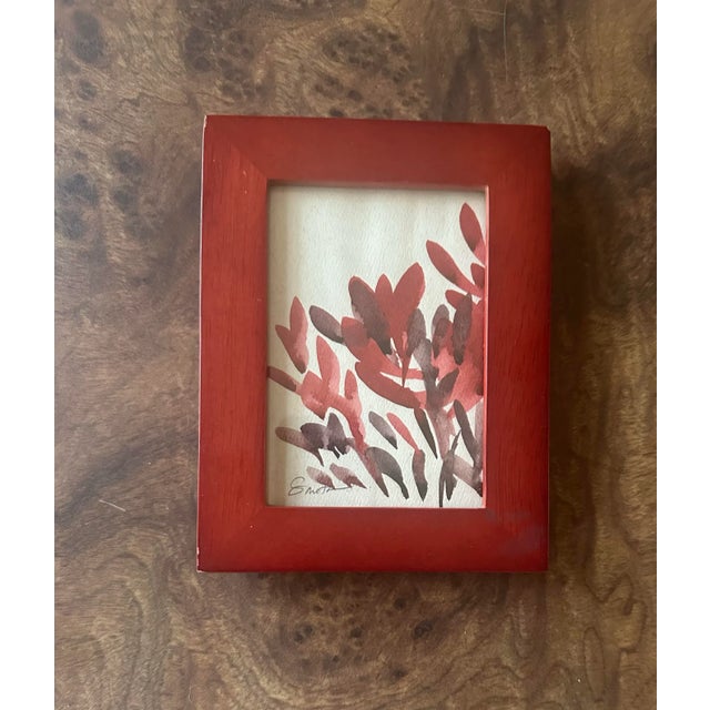 This minimal yet striking botanical watercolor features bold, organic brushstrokes in rich crimson and earthy tones. The...