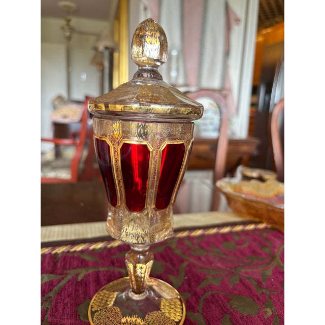 This ornate pedestal compote with a lid was purchased in Germany in the mid 1960’s. It features a deep ruby color with...