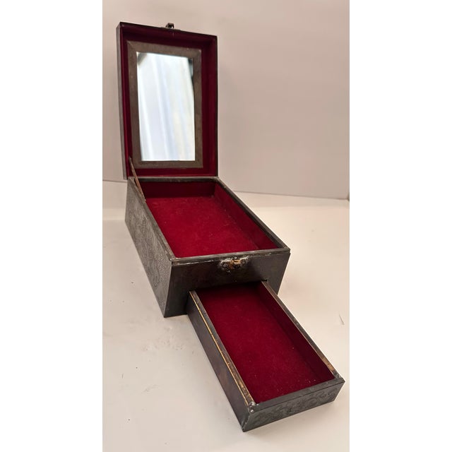 An antique bronze-clad box with a hinged lid that lifts to reveal a mirror inset into the underside, and a single pull-out...