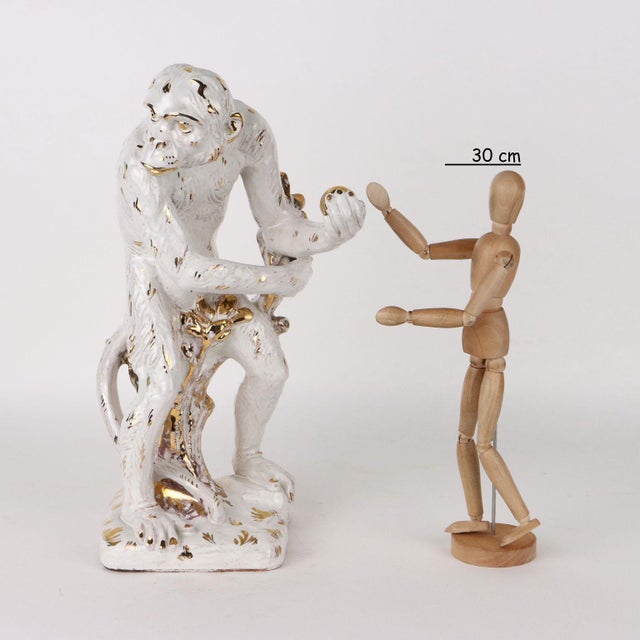 White glazed terracotta sculpture with gold decorations depicting monkey. This piece is attributed to the mentioned...