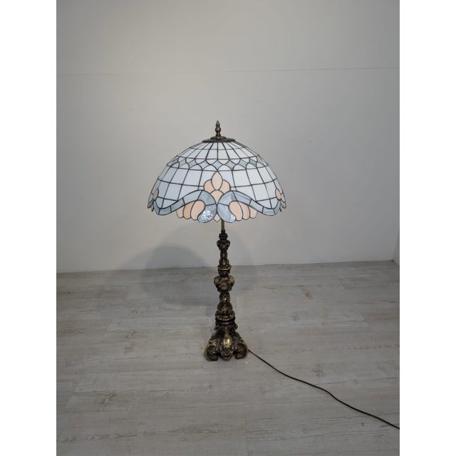 Tiffany-Style Brass Table Lamp Tiffany-style table lamp with a stained glass shade and a decoratively cast brass base. A...