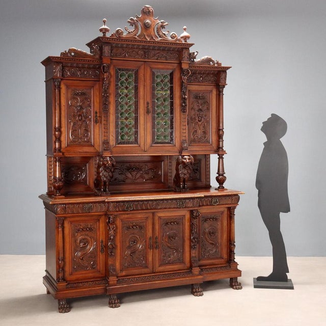 Neo-Renaissance-style sideboard in richly carved walnut. The upper part features a pair of central stained-glass doors and...