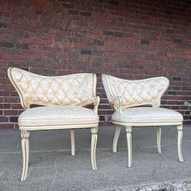 This is a pair of Louis XB style French accent chair. They feature a curved tufted back with gold and white floral accents...