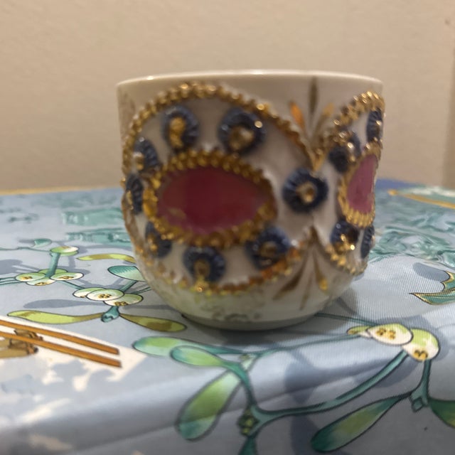 This stunning antique porcelain cup features a highly textured, hand-decorated design. It showcases vibrant pink central...