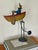 A charming vintage folk art sculpture of a man rowing in a rowboat, captured in a kinetic balancing composition. Crafted...